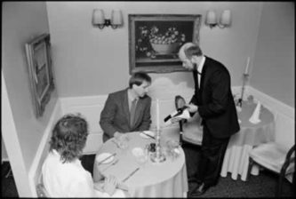 Philip Temple, Orsini's proprietor, presenting a bottle of wine to a customer, 1988