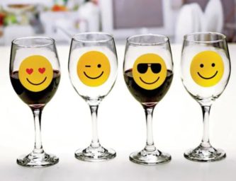 Novelty stemware glass set includes four cute glasses that each feature one popular yellow smiling emoji.